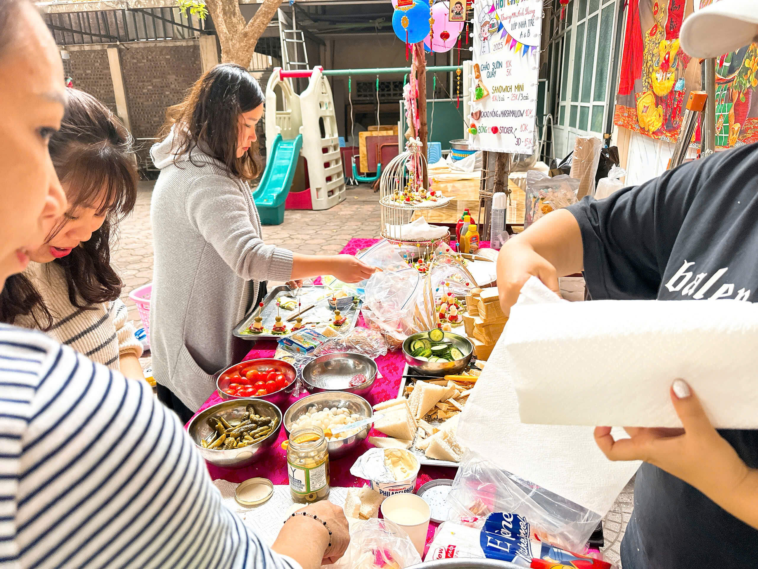 phụ huynh cùng cô giáo đang chuẩn bị cho gian hàng của mình